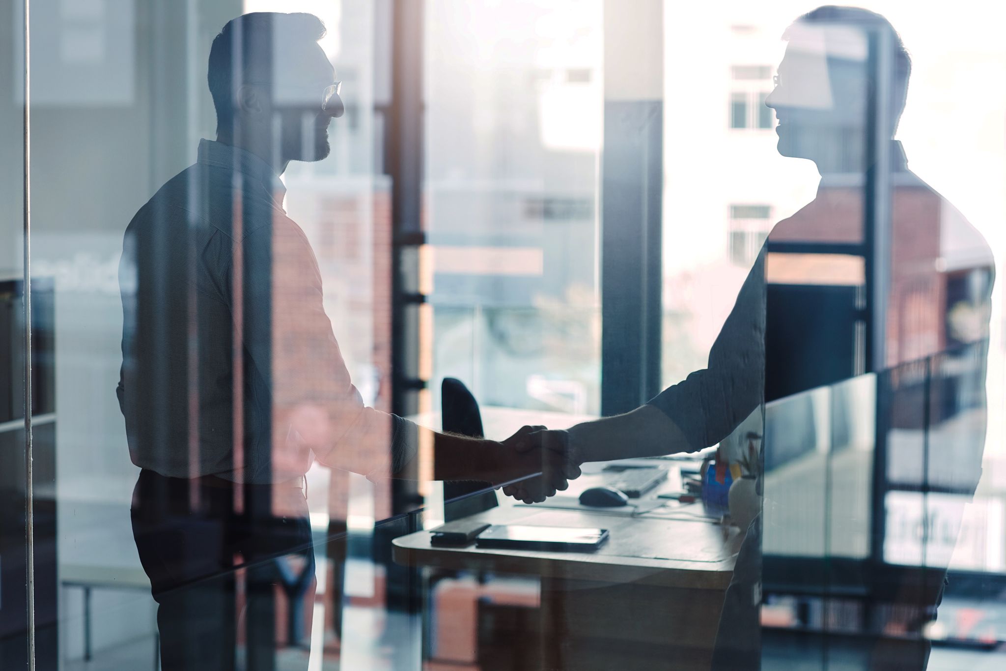 Sealing Deals with Mergers and Acquisitions Insurance | Two businessmen shaking hands, symbolizing successful partnerships and secure transactions.